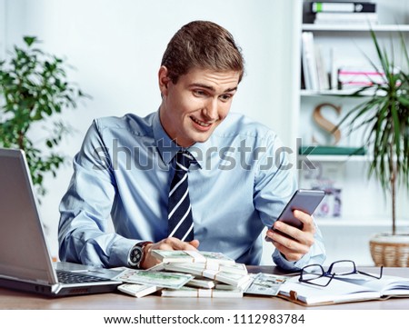 Good news! Office worker looking at the phone. Photo of happy young man working in the office. Business concept