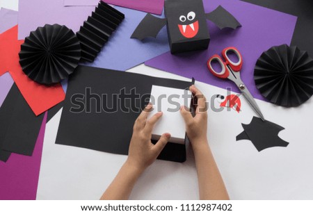A child making vampire bat Halloween decorations from colored paper. Master class bat gift box. Favorite hobby. Teaching a child. School, kindergarten. Hand making papercraft gift.