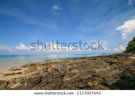 Nature landscape of sand and rock on the beach with blue sea and sky in summer
