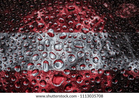 Close-up of a drop of water against a background of the national flag of Austria   on an isolated background