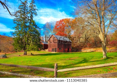 Trendition red wooden barn surround by blue sky, green grass and autumn trees. Vintage style photo was taken on the mountain in Fall season in New York, USA. Royalty-Free Stock Photo #1113040385