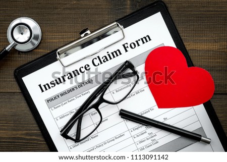 Health insurance claim form for fill out. Empty form near heart sign and stethoscope on dark wooden background top view