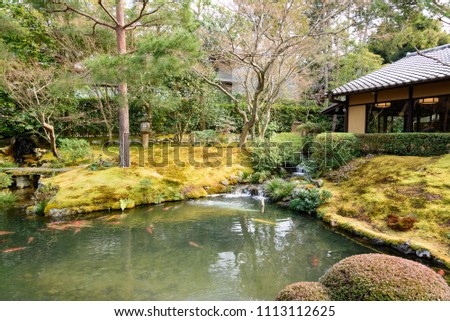 Japanese garden including trees, moss, pond and wooden building.