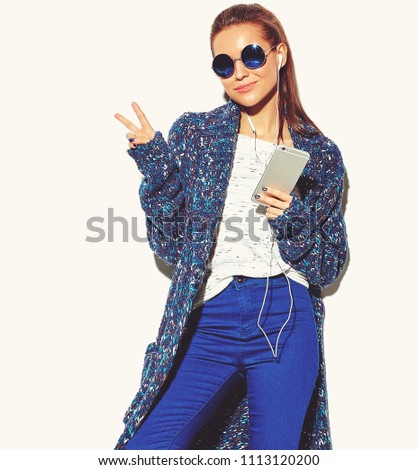 portrait of beautiful happy cute smiling brunette woman girl in casual blue hipster summer clothes with no makeup isolated on white in sunglasses listening music in smartphone with headphones 