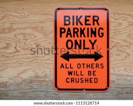 Biker parking only, all others will be crushed. Funny parking signal on wood background
