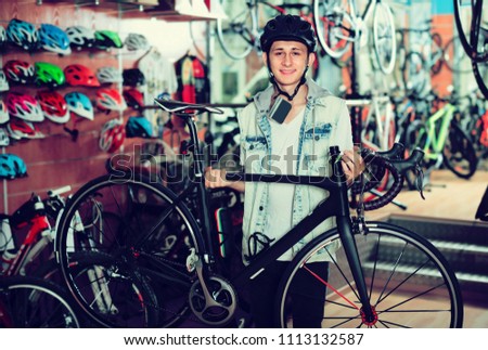 Smiling boy teenager 15-17 years old choosing new bicycle in sport hypermarket