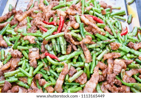 Stir fried long green beans and pork belly with red curry paste, Thai street food.