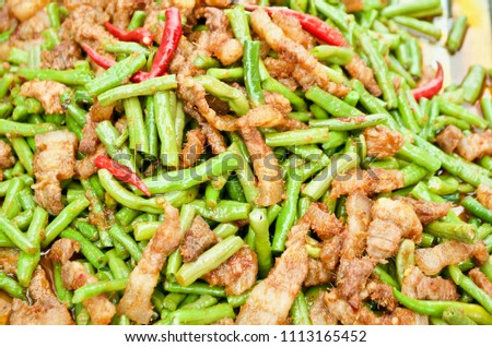 Stir fried long green beans and pork belly with red curry paste, Thai street food.