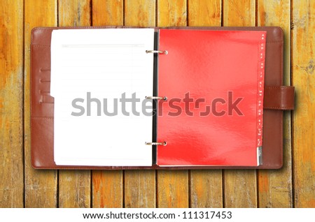Old brown leather cover notebook on wooden background