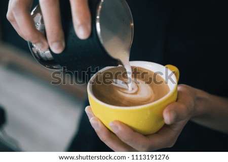 Closeup image of female hands pouring milk and preparing fresh latte, coffee artist and preparation concept, morning coffee