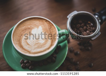 Cup of coffee Latte art  on wooden table with coffee beans,a cup of green pastel.