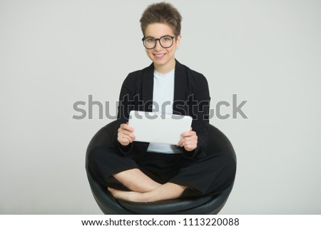 young beautiful girl with short hair on her head, in a suit and glasses with a tablet in her hands