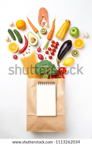 Picture of paper bag with vegetables, fruits and spaghetti isolated on empty white background.