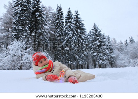 The frame depicts a winter forest, trees and pine trees. A child is playing with snow. Walk in the winter forest on vacation.