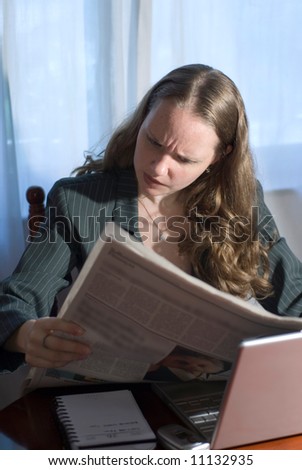 A woman sitting and thinking while reading the morning paper.