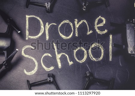 chalkboard inscription on the blackboard  drone school, near quadrocopter and its accessories, toned image