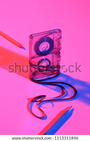 close up view of retro audio cassette and pencils on pink backdrop
