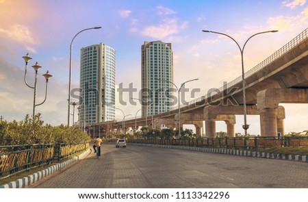 Tall city buildings with under construction over bridge alongside highway road at Rajarhat, Kolkata India.