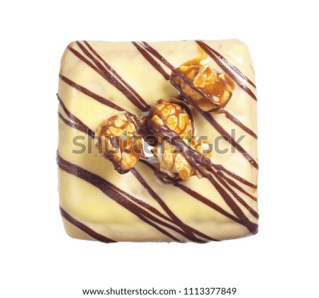 Square donut with a creamy glaze is decorated with roasted corn and chocolate stripes isolated on white background, top view