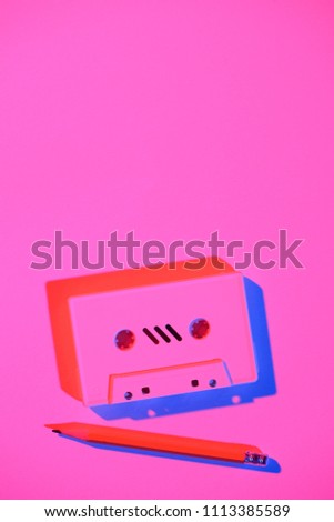 toned pink picture of retro audio cassette and pencil