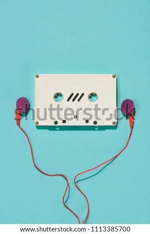 flat lay with white retro audio cassette and earphones isolated on blue