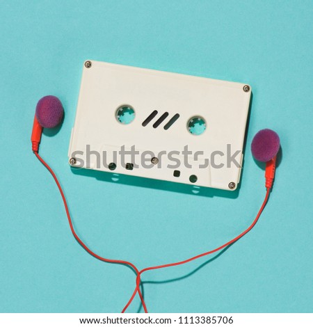 flat lay with white retro audio cassette and earphones isolated on blue