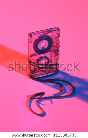 close up view of retro audio cassette and tape on pink backdrop