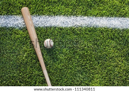 Baseball and baseball bat on grass field with white stripe viewed from above