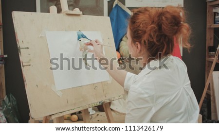 Young female artist painting still life in studio