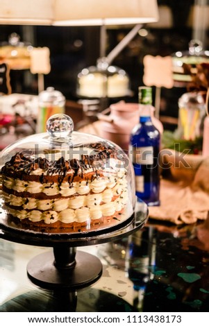 Tiramisu layer cake under glass bell dome. Cake stand, dessert buffet, storage. Food photography concept