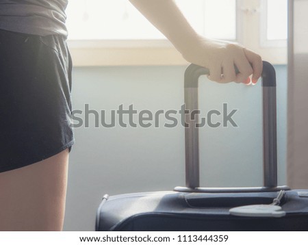 Travel and accessory concept from backside beauty woman hand stand and touch on luggage handle with window light background