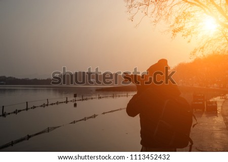 Silhouette traveler take a photo at lakeside of  Xihu Lake with frozen lotus, Hangzhou, China, while snowing in a winter day