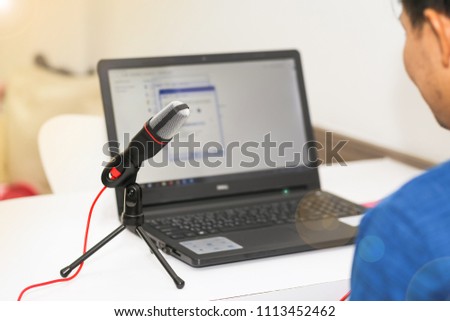 A man using a microphone with a computer notebook. Concept audio and studio recording.