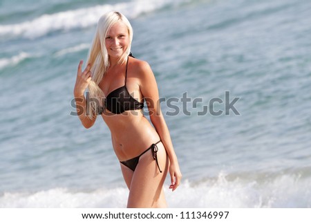 young happy beautiful woman in black bikini on sea background