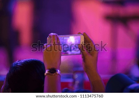 People are using mobile recording of a concert at night.