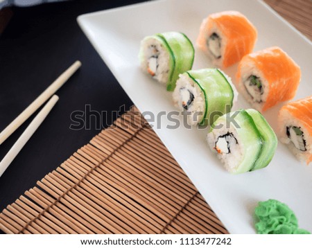 Philadelphia Sushi Roll with, cucumber, cream cheese, nori, avocado and maki roll with ginger, wasabi  served on plate. Space for text.