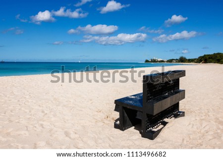 Black bench on a beach in Barbados.

Idyllic afternoon at the beach in Barbados (Caribbean island): Nobody, white sand, clear turquoise water with waves and a sunny blue sky white clouds