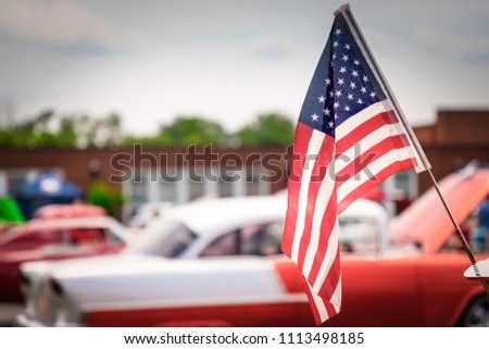 The wind blowing an American flag over a classic American fifties car at a Virginia show. Royalty-Free Stock Photo #1113498185