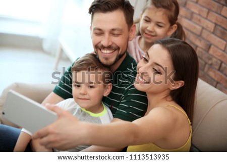 Young woman taking selfie with her family at home