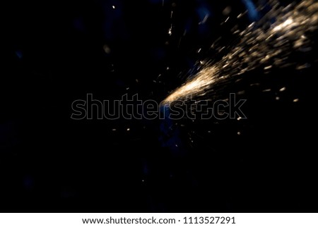 Fire sparks on a black background during metal cutting, hot burning element in flame.