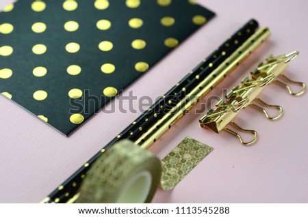 Top view flat layout of gold on black stationery on blush pink background with copy space. Female and lifestyle business and work from home concept.