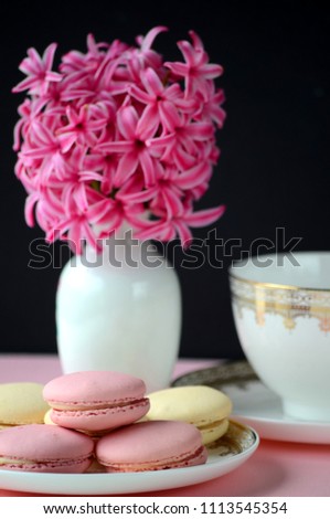 Bright pink hyacinth with French macarons, cup of coffee and gold black stationery on pink background. Female and lifestyle business and work from home concept. Spring theme. 