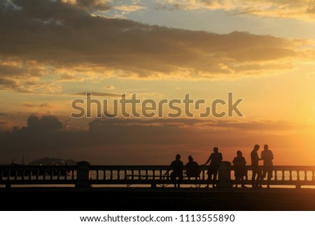 silhouette the people sweet and taking in park on sea sunset orange sky