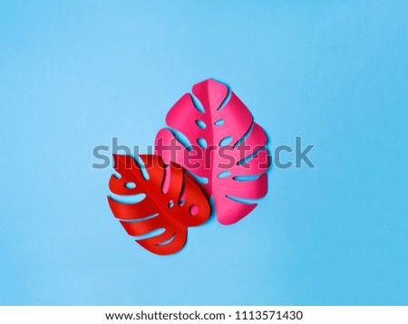 From above shot of two vivid leaves made of paper lying on blue background. Summer vibes. 