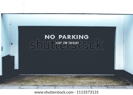 Black garage gate with sign: no parking day or night