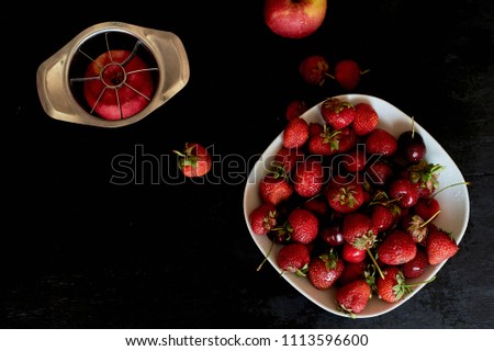Delicious and juicy fruits, red on black background. With water droplets. Cherry Apple and strawberry