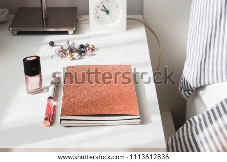 Rose gold glitter notebook and pen on a white table. Woman's stylish beauty accessories. Blogging, freelance, minimalism lifestyle concept