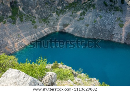 Blue Lake Imotski Croatia, Beautiful nature and landscape photo of very big,  deep sinkhole in Dalmatian mountains. Nice sunny summer day. Water, rocks and stones. Amazing place to visit on vacation.