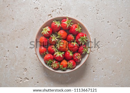 Juicy ripe strawberries in a bowl on bright rustic background