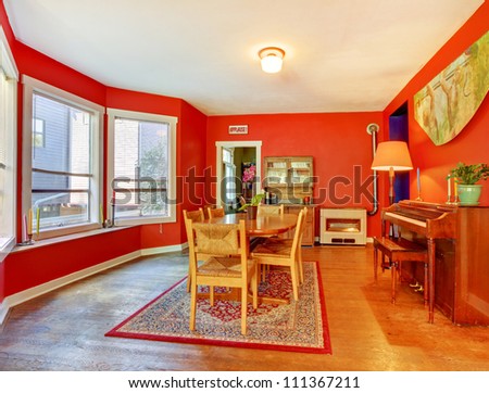 Red dining room with piano, hardwood floor and many windows.